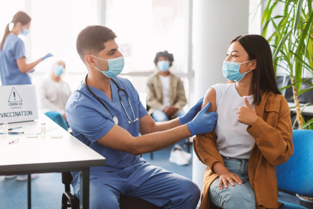 istock Vaccinated Asian Lady Gesturing Thumbs Up At Clinic 1347886792