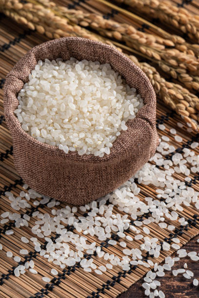 istock Raw white rice in a wooden bowl over table. 1347890119