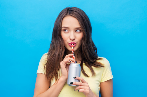 mujer joven o adolescente bebiendo refrescos de lata photo