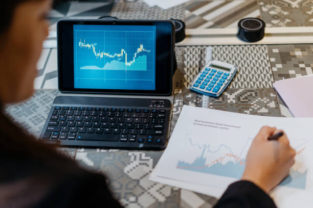 empresaria asiática revisando gráfico bursátil en tableta digital - economist fotografías e imágenes de stock