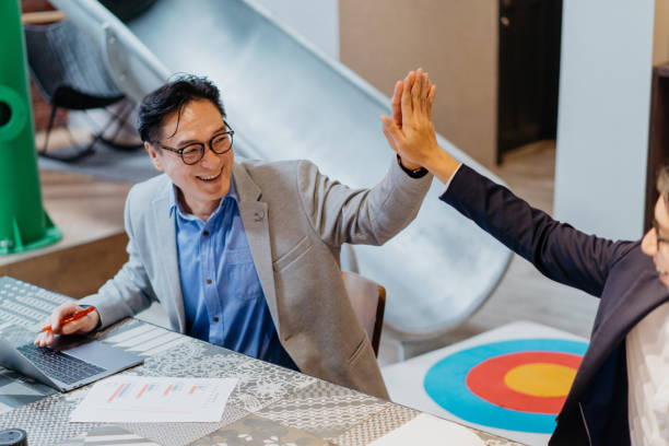 コワーキングオフィスで高5を与える2人の興奮したアジアのビジネスマン - asia businessman asian ethnicity happiness ストックフォトと画像