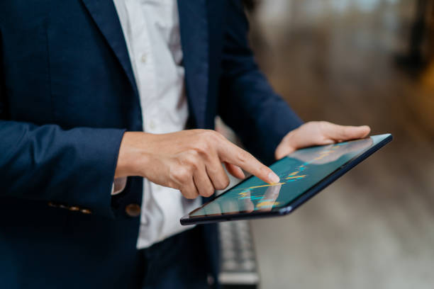 empresario asiático revisando gráfico bursátil en tableta digital - investigación de mercados fotografías e imágenes de stock