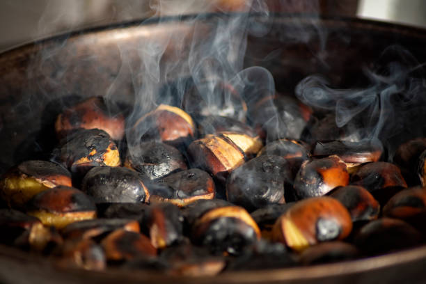 vista de cerca de castañas asadas en una sartén con humo - chestnut roasted heat roasted chestnut fotografías e imágenes de stock