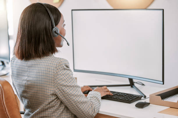 istock Rearview shot of a female call center agent wearing a headset while working on her computer in the office 1347891546