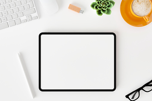 Top view of blank screen tablet on white working desk background.