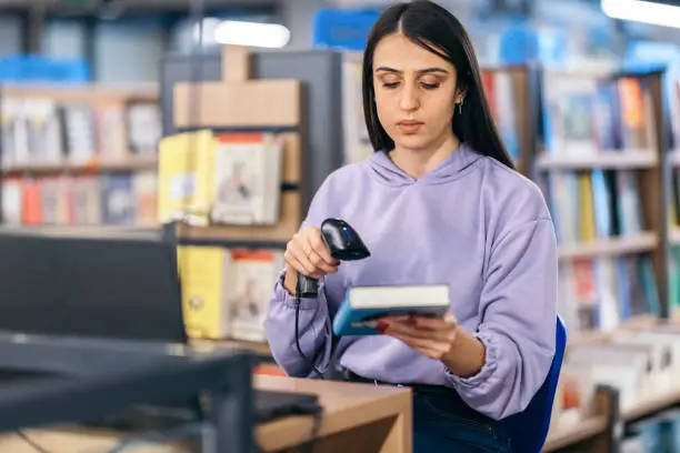 Photo of University student scanning a book in  library