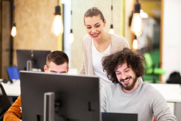istock Three caucasian colleagues cheering for job well done in a modern office with decorative hanging lightbulbs. 1347891816