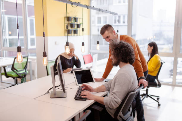 istock Business people having conversation in front of a computer. Modern multiethnic coworking office space. 1347891928