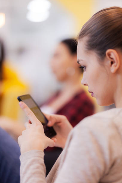 istock Beautiful girl using phone during creative meeting with coleagues. 1347891930