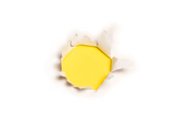 istock A hole in a white paper on a yellow background. 1347893112