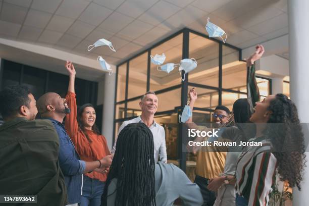 Shot Of A Group Of Businesspeople Removing Their Face Masks And Tossing Them Into The Air Stock Photo - Download Image Now
