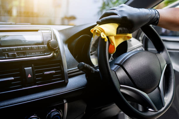 istock Worker hand wear glove cleaning console steering wheel with microfiber cloth yellow. hygiene prevention antibacterial of corona virus outbreak. 1347894588