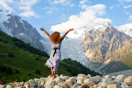 Young beautiful girl in a dress with red hair on the background of the Adishi glacier.