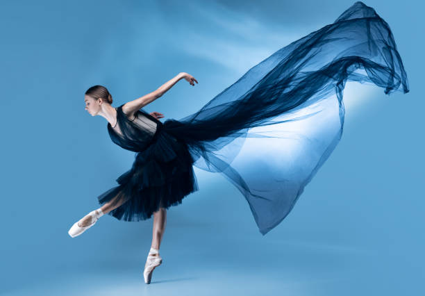 istock Young and graceful ballet dancer in black stage outfit, dress isolated on white blue studio background in neon light. 1347897018