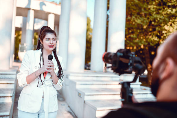 istock Smiling Female Reporter Making Statement About Latest News For Camera Man 1347906290