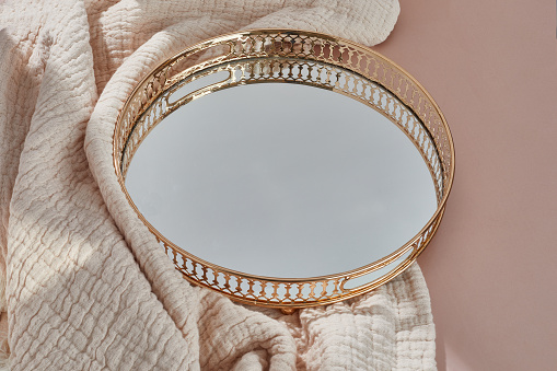 Golden mirror tray with pink blanket on pink background with copy space. Beauty product mock up.
