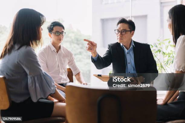 Perplexed Young Asian Woman Looking At Her Leader Pointing Fingers At Her Stock Photo - Download Image Now