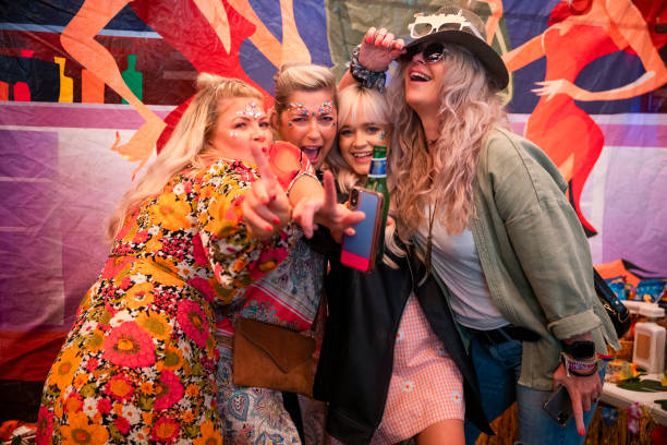 Friends Singing & Dancing Four caucasian woman dressed in festival clothing, accessories and makeup on an overcast summers day. They are having fun, singing and dancing at a festival themed hen party in a large marquee. festival goer stock pictures, royalty-free photos & images