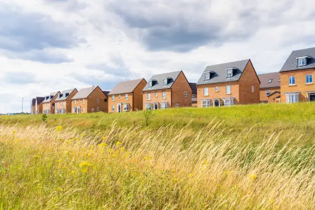A view across meadow grass to a new build housing estate near Milton Keynes, England.