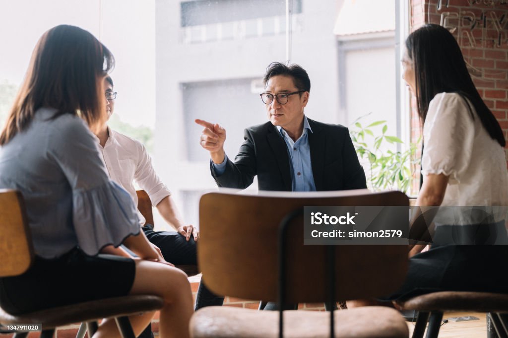 Angry leader pointing out his employee in bright office Disgruntled multiethnic team scolding female colleague who made bad work-related mistake. Conflict Stock Photo