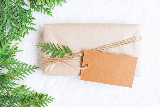 istock Wrapped surprise gift box with big text label on snowy winter background top view. New Year composition with copy space. 1347911995