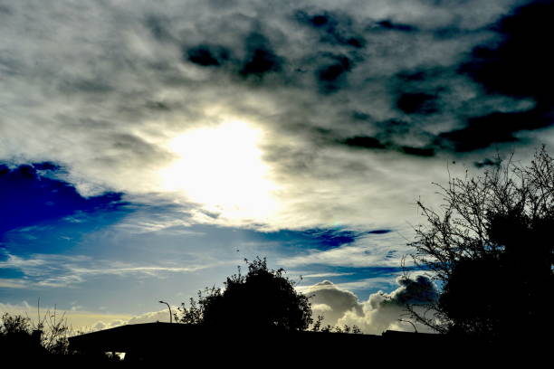 Autumn day, changeable weather  sun appears through a dramatic sky above a flat roof of a gas station