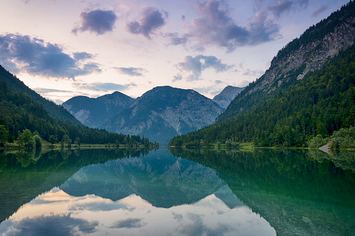 beautiful austrian mountain lake plansee with reflection of the mountains and clouds in the crystal clear calm water