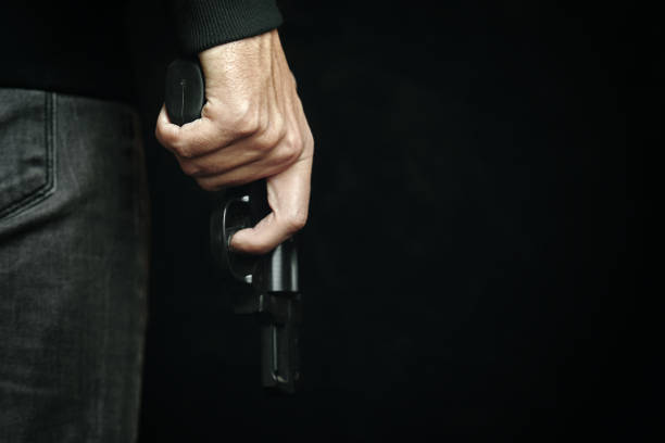istock Man in dark clothing is holding gun. 1347913961