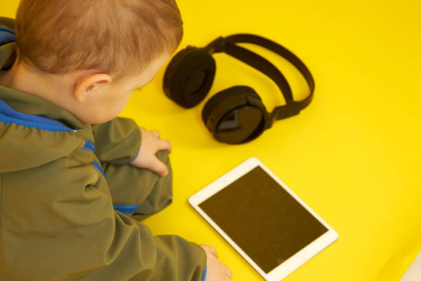 istock A child lying down uses a digital tablet on a yellow background 1347914373