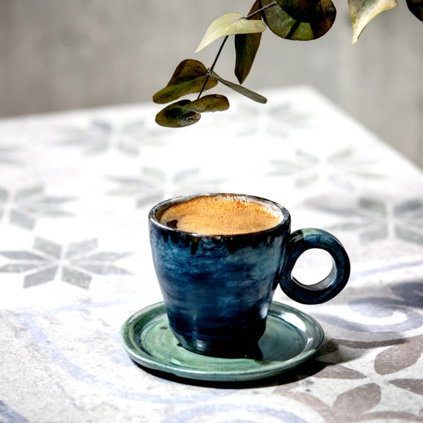 istock Cup of black coffee on ceramic table. Sun light, shadows 1347918892