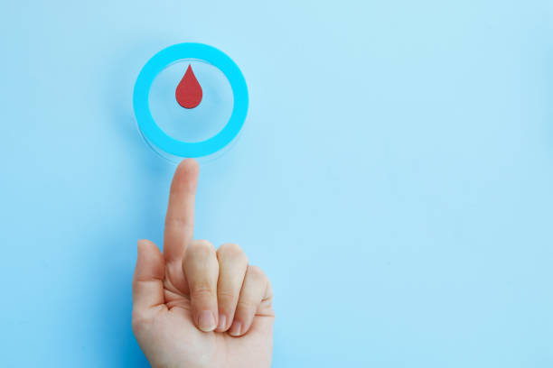 concienciación sobre el día mundial de la diabetes. mano de mujer con un círculo azul con gota de sangre, símbolo de la diabetes - diabetes fotografías e imágenes de stock