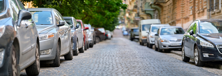 City traffic with cars parked in line on street side.