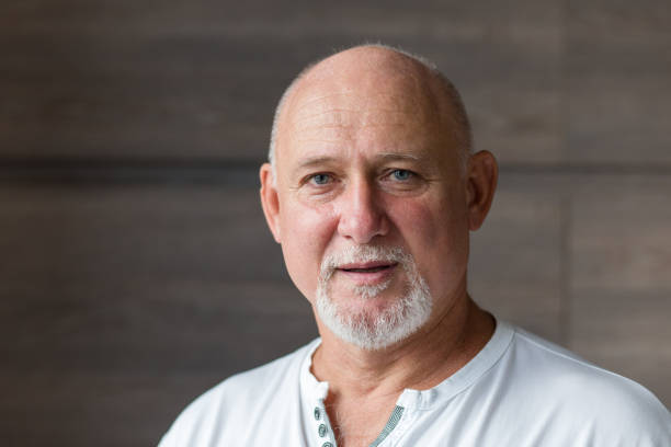 Middle aged man with folded arms bald and with white beard looking confident