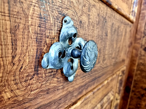 Antique door knob on a beautiful wooden door. The wooden dor was decorated by an old technique.