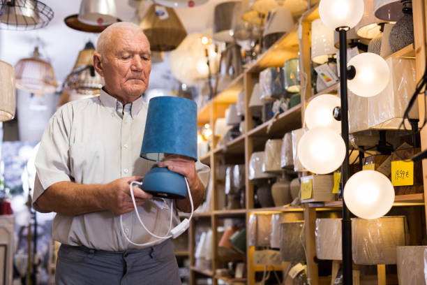 istock Mature man choosing table lamp at shop 1347930667