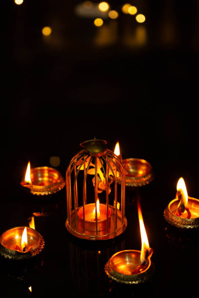 Top view of Multiple Brass Diya Illuminated with a decorative candle holder with Black Background and golden bokeh. Indian Festival Diwali Pooja, Navratri, Dussehra Puja, New Year stock photo