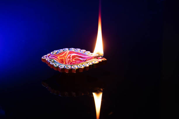 istock Mitti ka Diya Illuminated With Reflection Blue Gradient Black Background. Indian Festival Theme For Diwali Pooja, Navratri, Dussehra Puja, New Year, Deepawali, Or Shubh Deepavali 1347930828