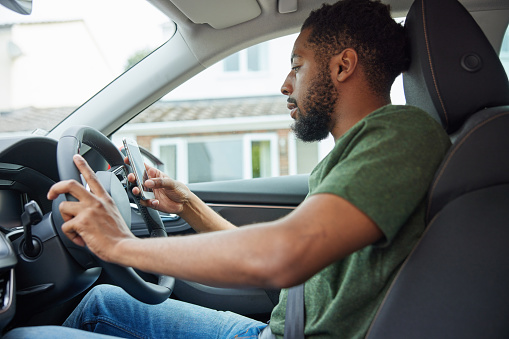 Man Using Mobile Phone Whilst Driving Car
