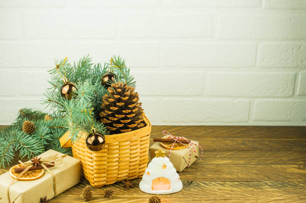istock Christmas festive composition on a wooden table. wicker basket with a large cedar cone, spruce branches, gifts and a hot candle. 1347935931