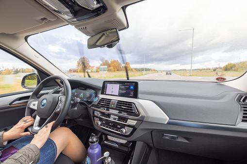 Sweden. Uppsala. 10.11.2021. Close up interior view of BMWiX3 on road. Female driver in vehicle.