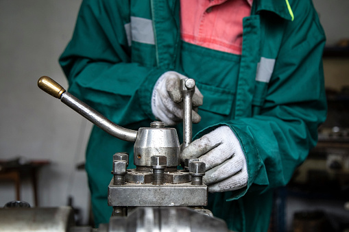 Young man with protective work wear and glasses repairing machines in his metallurgy workshop