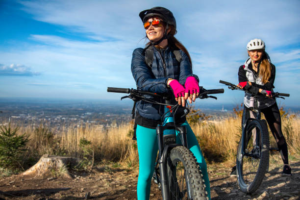 deux jeunes femmes en vélo électrique - mountain biking photos et images de collection