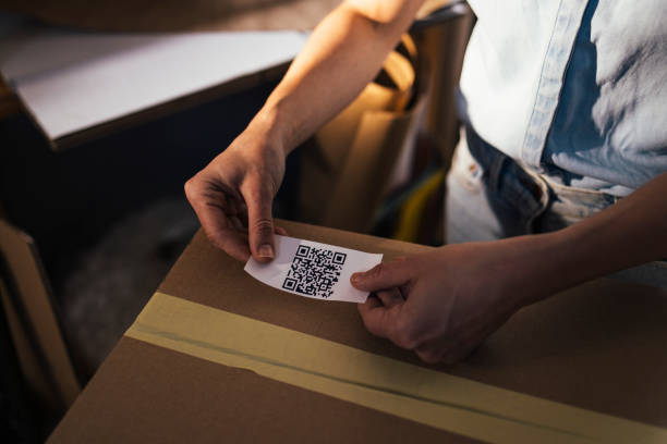 istock Anonymous Businesswoman Taping a QR Code onto a Cardboard Box Packed for Shipping 1347940541