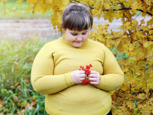 obese lonely girl in yellow clothes standing outdoors in autumn - child obesity imagens e fotografias de stock