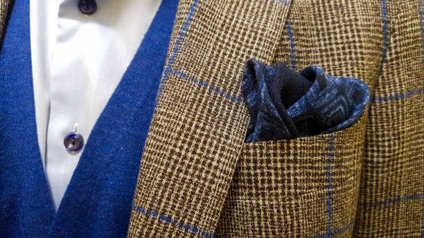 istock Brown suit jacket with blue squares over a light blue buttoned shirt and a sweater vest together with a matching blue cotton pocket square 1347944721