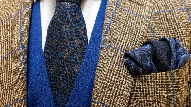 giacca marrone con quadrati blu sopra una camicia abbottonata azzurra e un gilet maglione insieme a una tasca quadrata in cotone blu abbinata e una cravatta floreale blu scuro - necktie garment fashion clothing foto e immagini stock