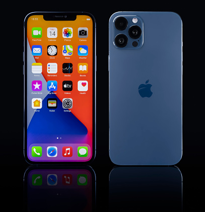 Galati, Romania - October 14, 2021: Studio shot of new Apple iPhone 12 Pro Max blue color, display front home screen, back view with Apple logo. Isolate on black background. Illustrative editorial