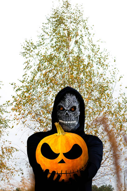портрет мрачного жнеца крупным планом. человек в посмертной маске с огненным пламенем в глазах на фоне желтой березы. карнавальный костюм, � - masc стоковые фото и изображения