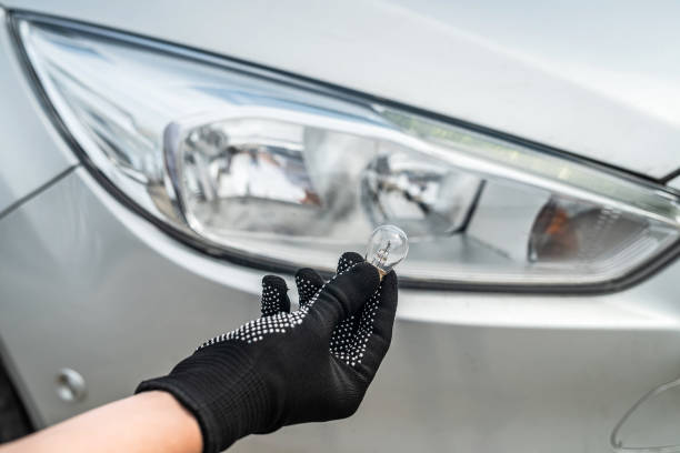 istock manual worker is changing a light bulb of the car 1347951332