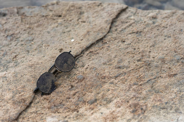 sunglasses covered with algae and washed up on coastal rocks during a storm